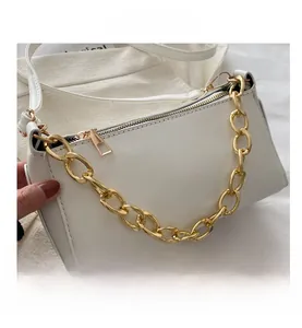 Close-up of white leather shoulder bag with bold gold chain link and zipper detail