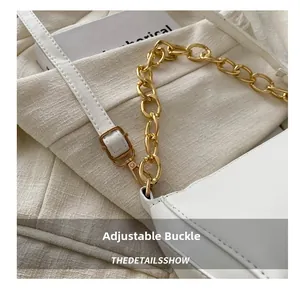 Detail of adjustable leather strap with gold buckle and chunky chain on white handbag