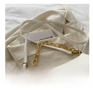Detail shot of a cream white shoulder bag with gold chain strap on beige blazer