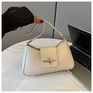 Dettaglio di una borsa baguette beige con chiusura metallica a stella d'argento su tavolo