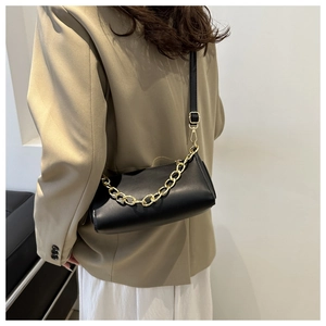 Close-up of minimalist black PU leather bag with decorative gold chain on a model
