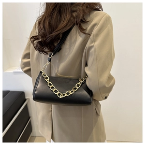 Detailed view of black matte underarm bag with gold chain strap on a khaki blazer