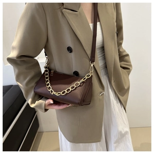 Detail of dark brown cylindrical shoulder bag with gold chain and crossbody strap