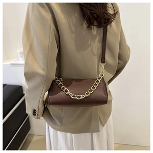 Close-up of a coffee brown crossbody bag with a chunky gold chain and leather strap