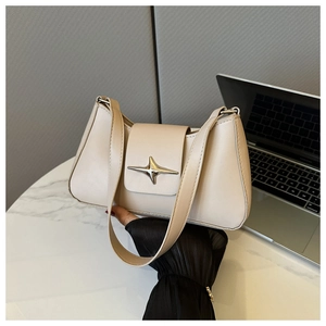 Dettaglio di una borsa in pelle beige con chiusura metallica a stella su marmo