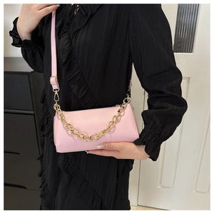 Detail of pink PU leather crossbody bag with chunky gold chain strap and smooth texture