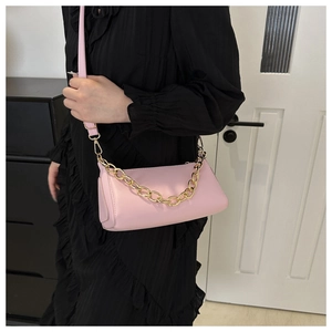 Close-up of pink baguette bag with adjustable leather strap and chunky gold chain detail
