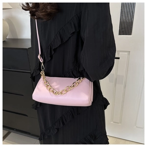 Detail of pink rectangular handbag featuring gold chain and thin leather shoulder strap