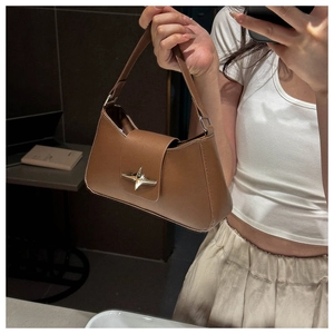 Dettaglio di una borsa baguette marrone con fibbia metallica argentata a forma di stella