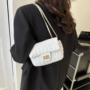 White quilted saddle bag with gold chain strap and twist lock, shown on a female model