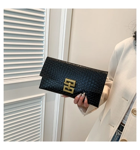 Détail de la pochette enveloppe noire en similicuir avec texture crocodile et fermoir doré