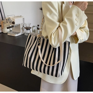 Detailed view of striped tote bag with woven texture and gold chain strap detail