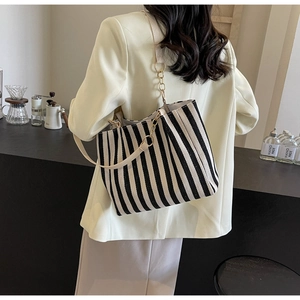 Detailed side view of black and white striped canvas tote bag with cream shoulder strap