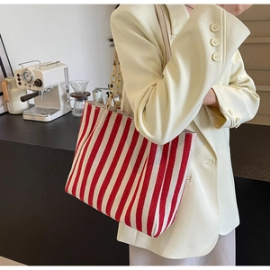 Detail of red and white striped tote bag featuring a gold chain and leather shoulder strap