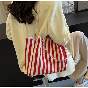 Detail of red and white striped canvas tote bag with gold chain and leather strap