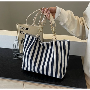 Detail of striped tote bag showing durable canvas texture and golden metal chain handle