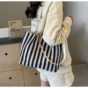 Detail view of large striped canvas tote bag with chain strap and elegant pleated side design