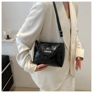 Detail of minimalist black faux leather shoulder bag with chain strap and fashion label