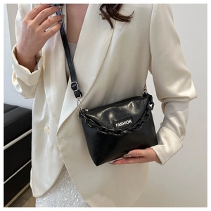 Detail of black acrylic chain handbag featuring a fashion label and adjustable strap