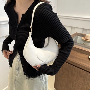 White crescent hobo bag with embossed heart pattern and gold hardware on female model