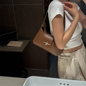 Sac à bandoulière marron avec boucle étoile dorée porté par un mannequin