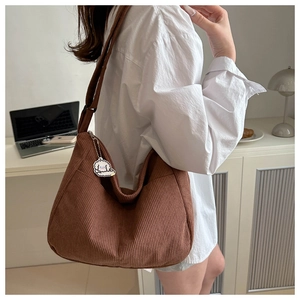 Close-up of brown corduroy hobo bag texture with a cute white dog charm pendant