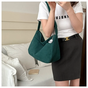 Close-up of green corduroy hobo bag with white dog charm shown in a mirror selfie style