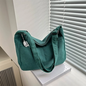 Detalle de bolso de pana verde oscuro con bolsillo lateral y colgante de perro de felpa