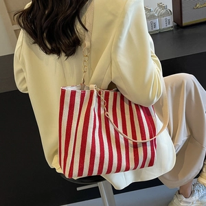 Red and white striped canvas tote bag with chain strap shown on model in a modern setting