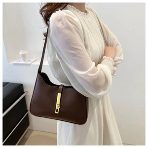 Detail of dark brown leather underarm bag with elegant gold metal buckle on model