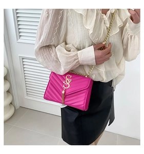Detail of fuchsia leather crossbody bag featuring chevron quilting and golden tassel