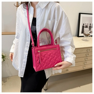 Detail of rose red quilted crossbody bag with gold zipper and adjustable shoulder strap
