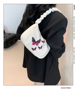 Detail of white shoulder bag with butterfly print and stylish ruched strap on model