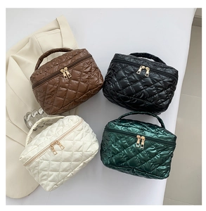 Overhead view of quilted cosmetic bags in brown, black, cream, and dark green with gold zippers