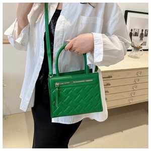 Detail of bright green crossbody bag with woven texture and decorative metal zippers