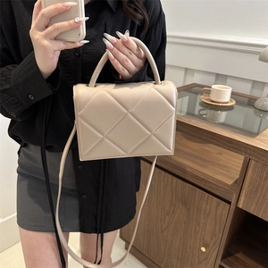 Elegant beige quilted handbag with soft leather texture and golden shoulder strap rings