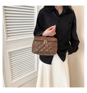 Close-up of brown quilted handbag featuring diamond stitching and dual metal zippers