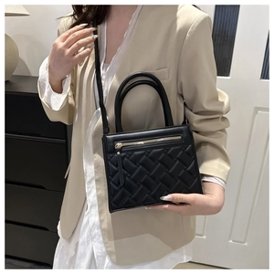 Close-up of black quilted woven texture handbag with gold zipper and curved handle detail