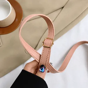 Detail of adjustable pink leather shoulder strap with gold metal buckle on a beach bag