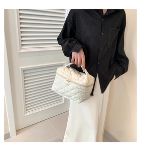 Detail view of the white quilted crossbody bucket bag with chain strap and metal zippers