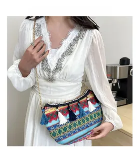Detail of colorful woven bohemian crescent bag with tassels and gold chain strap