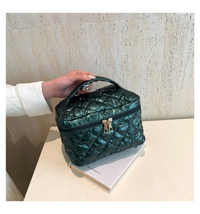 Detail of dark green quilted bucket bag with golden zipper and top handle texture