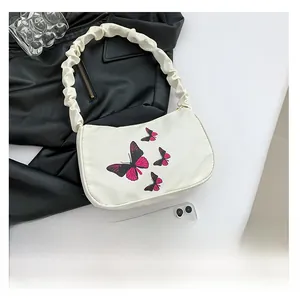 Detail of butterfly print pattern and ruched handle on cream shoulder bag for women