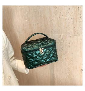 Macro view of dark green quilted vanity bag with shiny texture and golden dual zippers