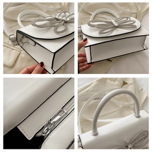 Detalle del bolso de cuero blanco con lazo grande de diamantes y bordes negros en contraste