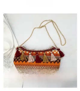 Detail of ethnic style woven crossbody bag with colorful tassels and gold chain strap