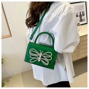 Detalle de bolso de cuero verde con una gran hebilla de mariposa en pedrería plateada