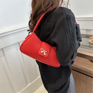 Chic red crescent underarm bag with golden bow buckle on model against modern wall