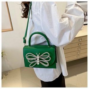 Detalle de bandolera verde esmeralda con decoración de mariposa de strass brillante