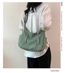 Detail of green nylon crossbody bag with dual vertical zippers and woven pullers